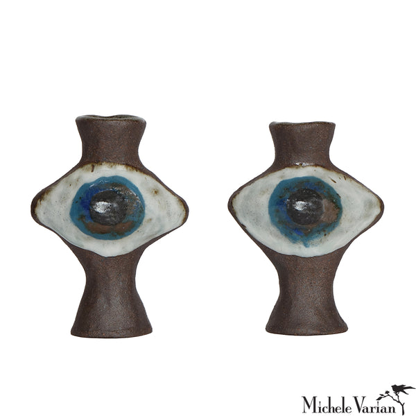 Two ceramic eye-shaped candleholders with brown, white, and blue design on a white background.