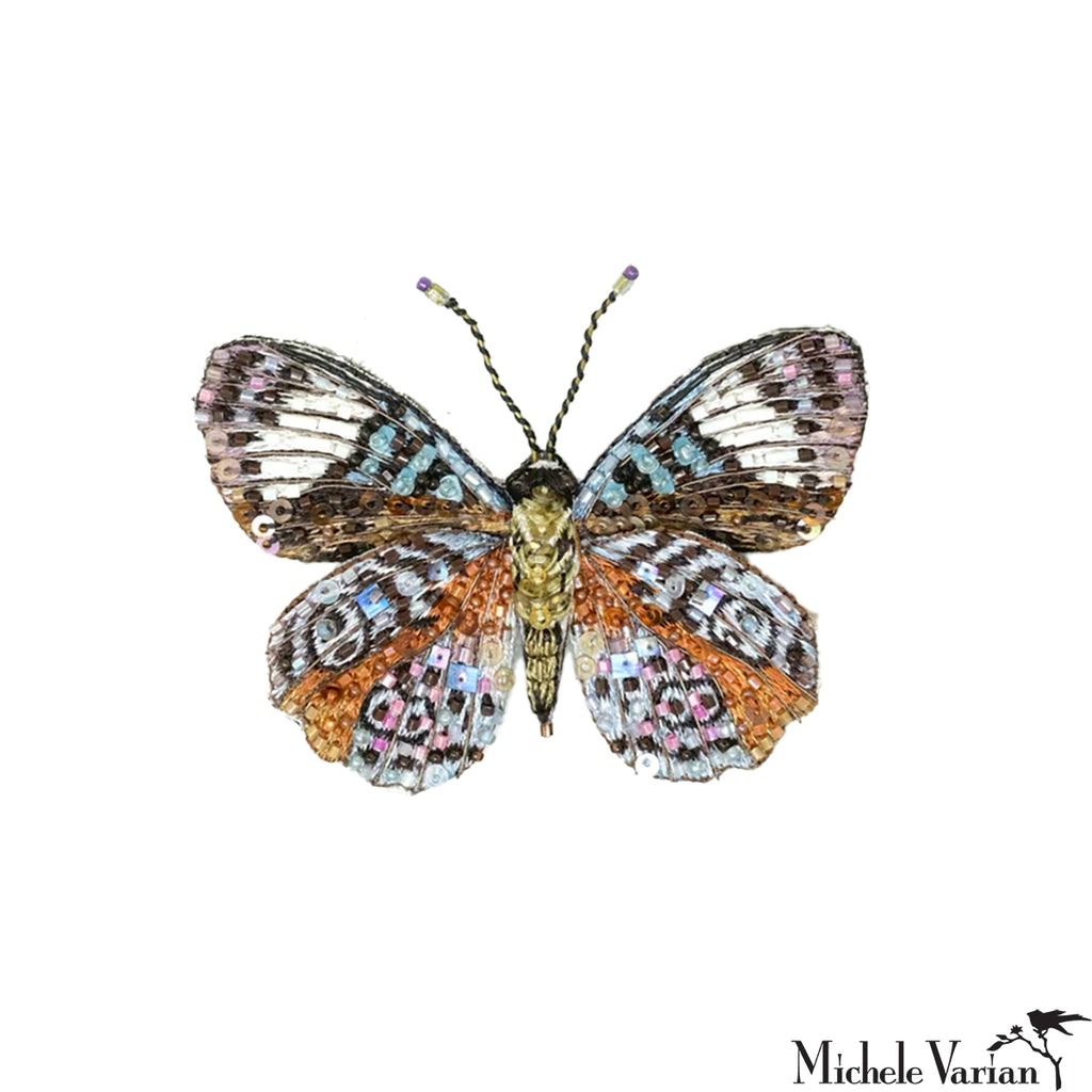 Colorful beaded butterfly pin on a white background