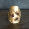 Gold ring with embedded red stones on a dark surface