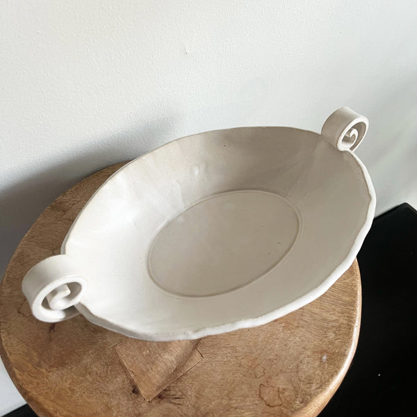 White ceramic bowl with decorative handle on a wooden surface