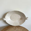 White ceramic dish with handles on a wooden surface against a light background