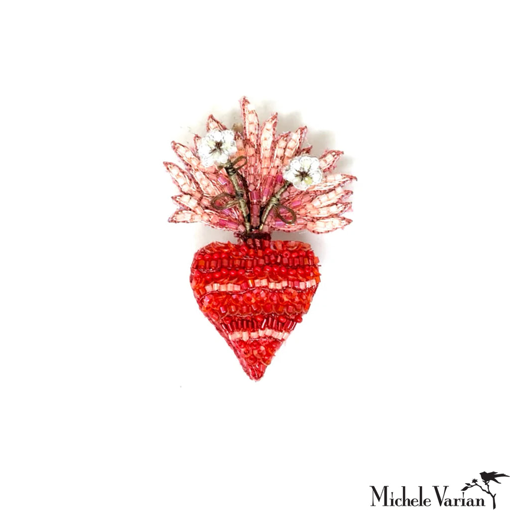 Decorative brooch with red heart design and floral top on a white background