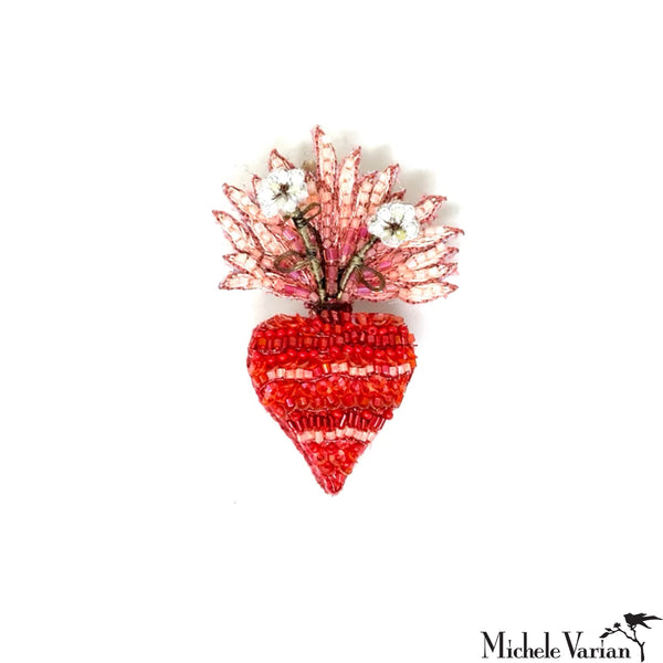 Decorative brooch with red heart design and floral top on a white background