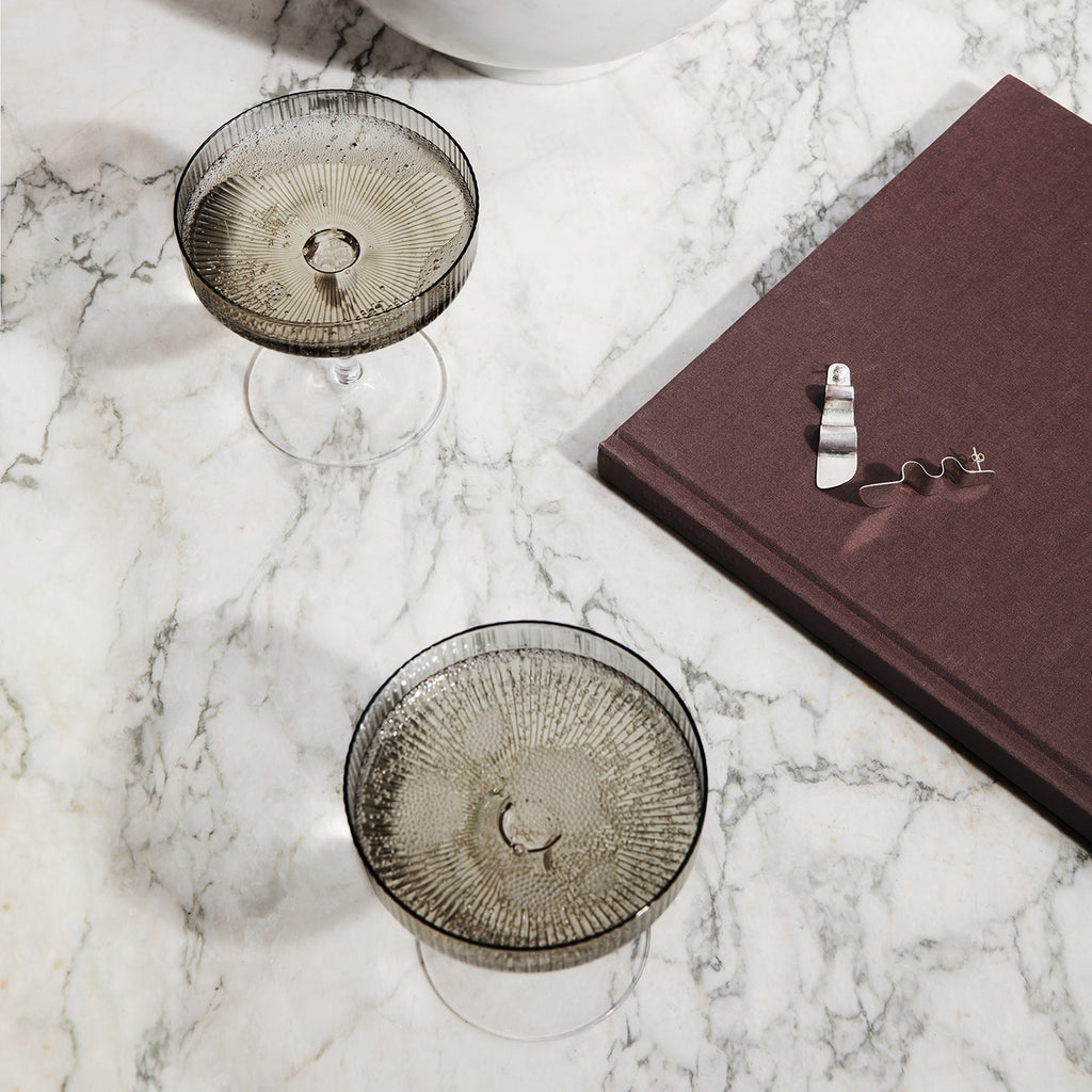 Two decorative glasses on a marble surface with a book.