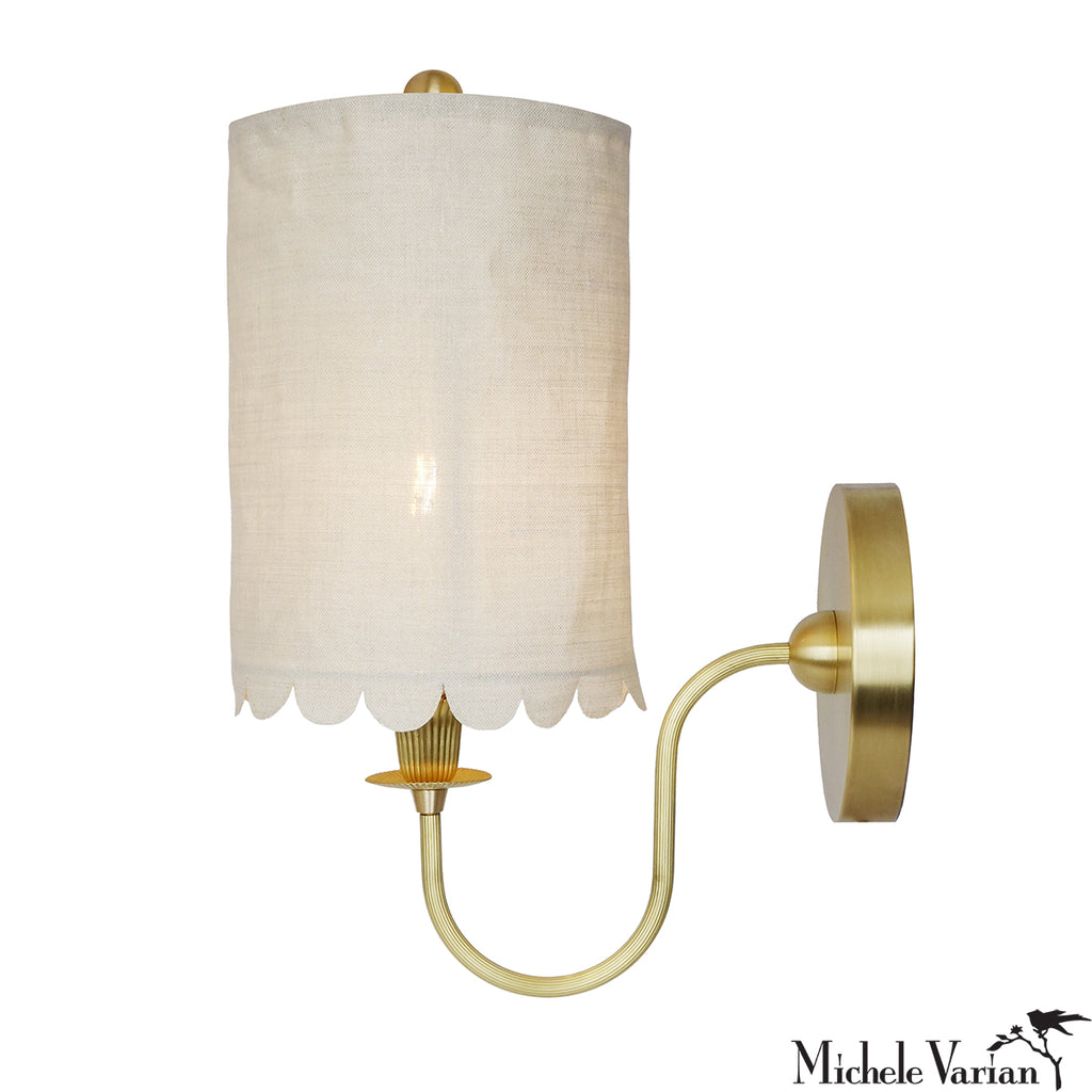 Wall sconce with white scalloped shade and brass detail and base, on a white background, designed by Michele Varian.