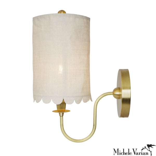 Wall sconce with white scalloped shade and brass detail and base, on a white background, designed by Michele Varian.