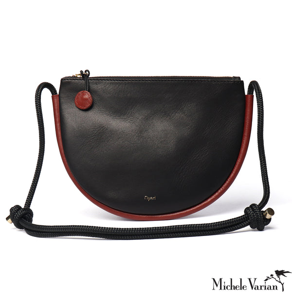 Black leather handbag with brown accents and a black strap on a white background