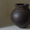 Brown ceramic vase with a knot design on a neutral background