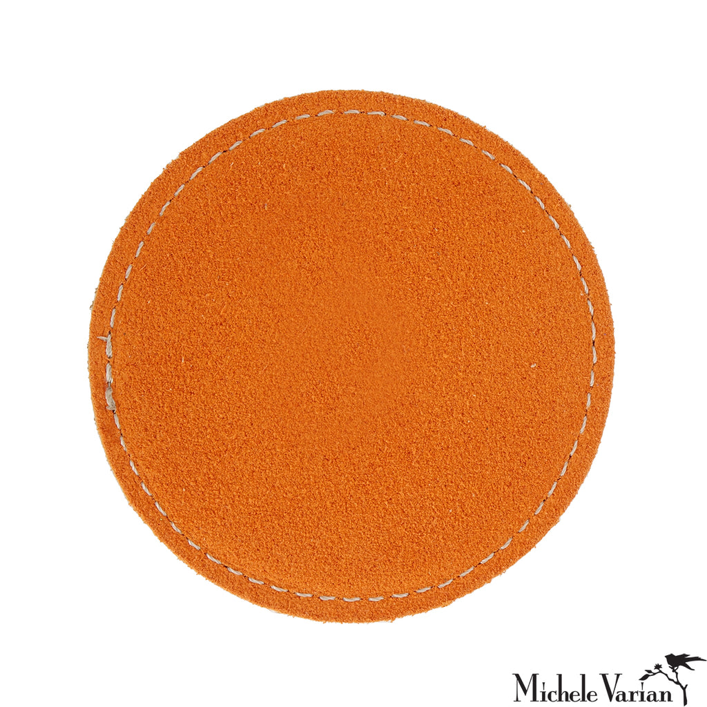 Orange circular drink coaster with white stitching on a white background.