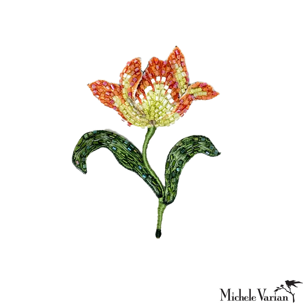 Decorative flower brooch with orange and green colors on a white background